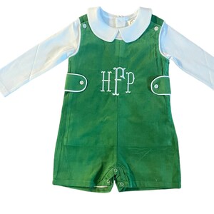 May include: A green romper with white piping and a white long-sleeved shirt. The romper has a white embroidered monogram "HFP" on the front.