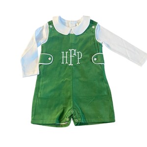May include: A green overall romper with a white collared shirt and long sleeves. The romper has a white embroidered monogram "HFP" on the front.
