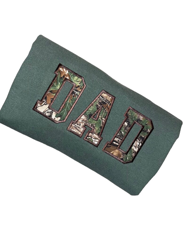 May include: A green sweatshirt with the word "DAD" embroidered in a camouflage pattern.