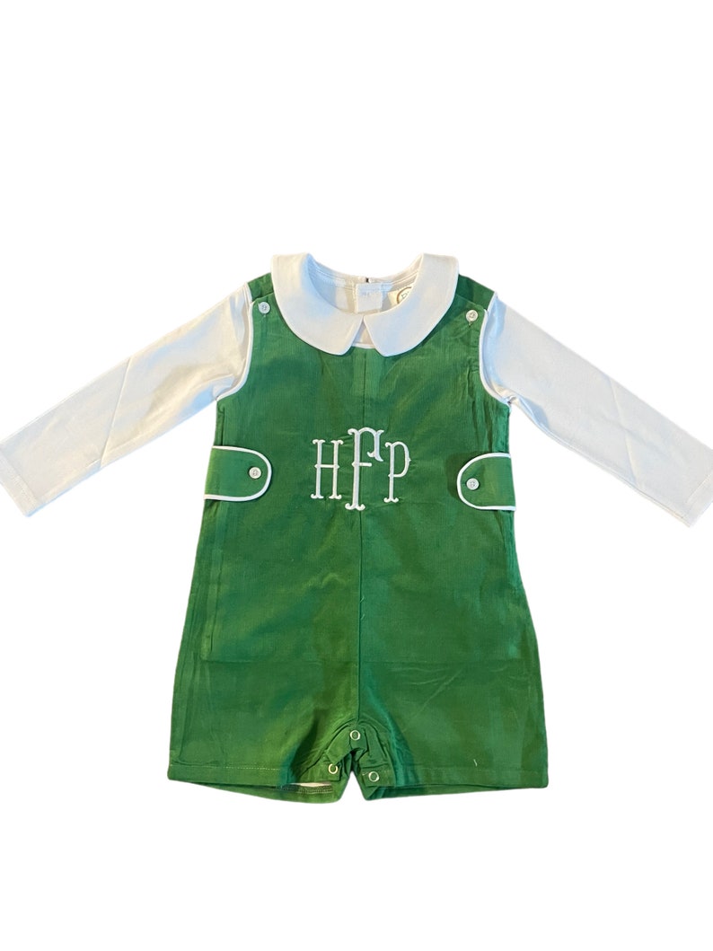 May include: A green and white baby outfit with a white collared shirt and green overalls. The overalls have white piping and a white monogram that says "HFP".