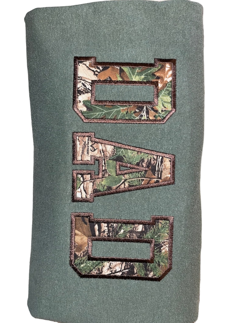 May include: Green sweatshirt with the word "DAD" embroidered in brown with a camouflage pattern.