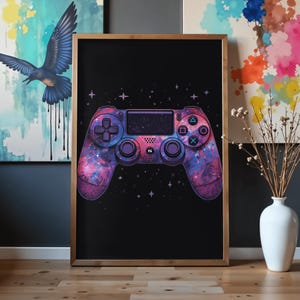 May include: A framed rectangular wall art print featuring a black background with a central video game controller graphic. The controller is decorated with a vibrant purple, pink, and blue galaxy nebula pattern, accented by small white stars.