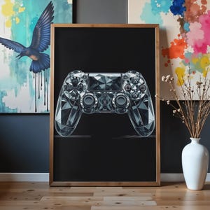 Peut inclure: Une impression murale rectangulaire encadrée représentant une manette de jeu vidéo stylisée, géométrique et à facettes de diamant, dans des tons gris et blancs sur un fond noir uni, le tout dans un cadre en bois clair.