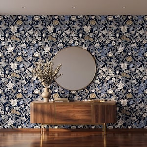 May include: A room featuring a dark blue floral wallpaper with white, gold, and blue accents. A round mirror hangs on the wall above a wooden cabinet with gold legs. A vase with dried flowers sits on the cabinet.