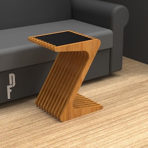 Puede incluir: Una mesa auxiliar de madera con una tapa negra y un diseño único en forma de Z. La mesa está hecha de madera clara y tiene un estilo moderno y minimalista.