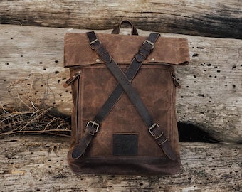 May include: A brown leather backpack with adjustable straps and buckles. The backpack has a flap closure and a small patch on the front.