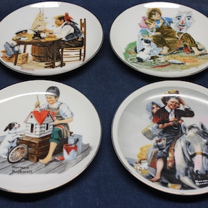 Puede incluir: Juego de cuatro platos coleccionables de Norman Rockwell con ilustraciones de niños. Los platos son blancos con ribete dorado y llevan la firma del artista.