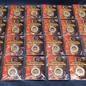 May include: Twenty-four plastic-wrapped trading cards featuring the Calgary Flames logo and the text "2003-04 Officially Licensed MEDALLION COLLECTION". Each card features a different player from the team and a small metal medallion.