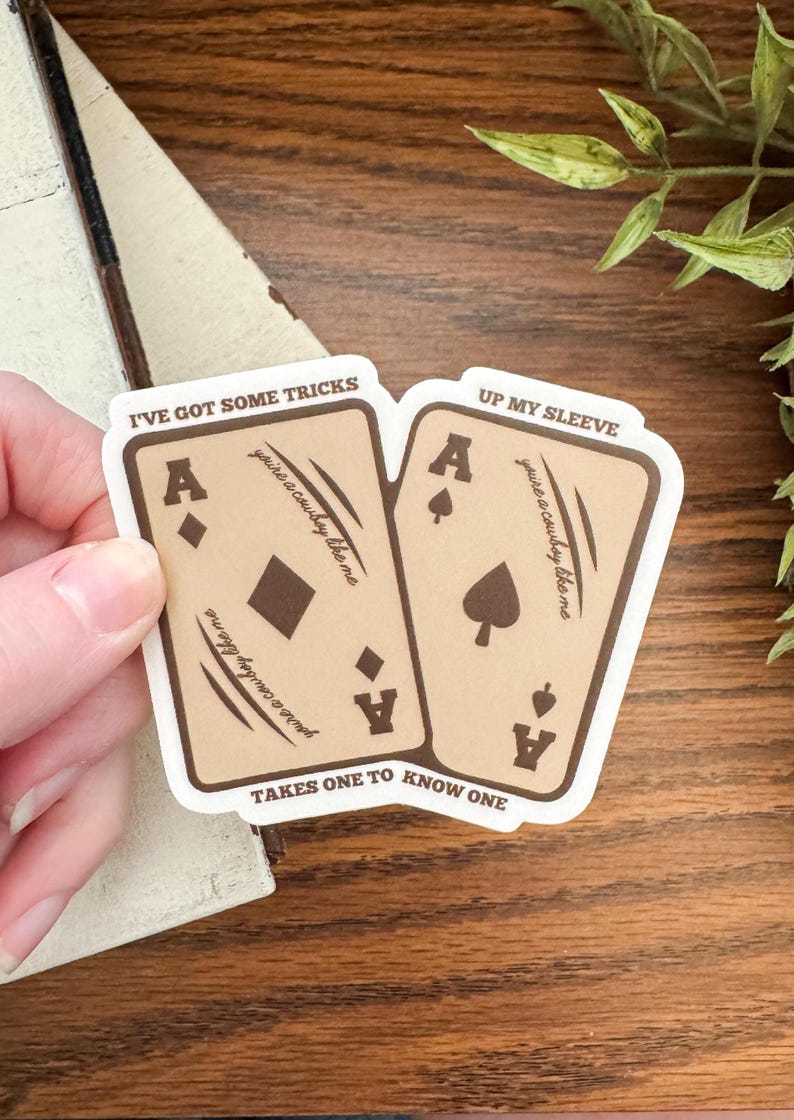 May include: Two playing card stickers featuring the Ace of Diamonds and Ace of Spades. The cards are tan with brown text that reads "I've got some tricks" and "Up my sleeve". The text "you're a cowboy like me" is also printed on the cards.
