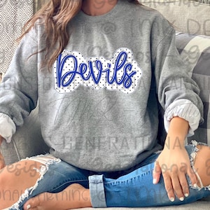 Może przedstawiać: Szara bluza z wzorem w niebieskie i białe kropki. Słowo "Devils" jest napisane niebieskim kolorem z białym obramowaniem.