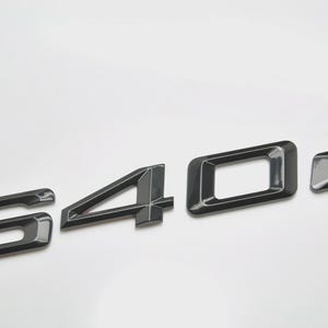May include: Black metallic "640d" emblem. The emblem features a stylized font with a glossy finish. The numbers are separate and arranged horizontally against a white background. The "6" and "4" have a more complex design.
