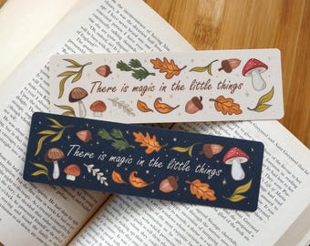 May include: Two decorative bookmarks with the text "There is magic in the little things." One is navy blue, the other is white. Both feature illustrations of mushrooms, acorns, and leaves.