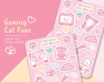 May include: Two sheets of pink matte vinyl stickers featuring a variety of cute cat-themed gaming designs. The stickers include a cat wearing headphones, a cat holding a controller, a cat in a litter box, a cat watching TV, and other cute designs. The text "gaming cat paws" is featured on both sheets.