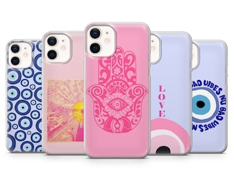 Pode incluir: Cinco capas de telefone diferentes com vários designs. As capas são todas transparentes e têm um fundo rosa. Os designs incluem uma mão de hamsa, um mau-olhado, um padrão de espiral, um pôr do sol e a palavra "LOVE".