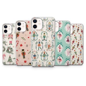 Könnte beinhalten: Fünf Handyhüllen mit weihnachtlichen Designs. Die Hüllen zeigen Muster von Nussknackern, Weihnachtsbäumen und Ornamenten in Rosa, Grün und Weiß. Die Designs erzeugen eine festliche Weihnachtsatmosphäre.