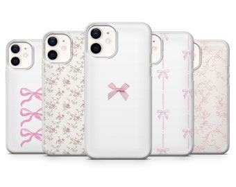 Pode incluir: Uma coleção de capas brancas para iPhone com vários designs em rosa. Os designs incluem laços rosa, padrões florais e um padrão de laços repetidos. As capas estão dispostas em fila, mostrando os diferentes estilos.