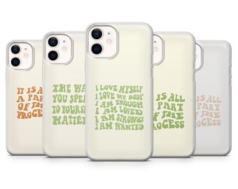 Puede incluir: Conjunto de cinco fundas transparentes para teléfono con diferentes afirmaciones positivas impresas en verde y naranja sobre un fondo crema. Las afirmaciones son "Es parte del proceso", "La forma en que pasas tu tiempo importa", "Me amo a mí mismo, amo mi cuerpo, soy suficiente, soy amado, soy fuerte, soy deseado", "Todo es parte del proceso", y "Todo es parte del proceso".