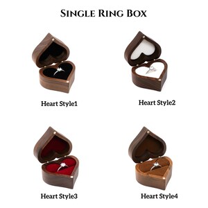 May include: Four different styles of wooden heart-shaped ring boxes. Each box is open and has a ring inside. The boxes are made of dark wood and have a velvet interior. The ring boxes are labeled "Heart Style 1", "Heart Style 2", "Heart Style 3", and "Heart Style 4".