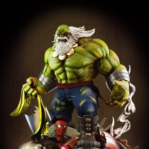 Può includere: Una statuetta verde di Hulk con una barba bianca e una collana d'oro. Hulk è in piedi su un mucchio di elmi e scudi di supereroi rotti, tra cui lo scudo di Capitan America, l'elmo di Iron Man e il martello di Thor.