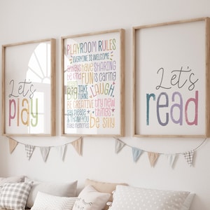 May include: Three framed prints with colorful text. The left print says "Let's Play" in rainbow colors. The middle print says "Playroom Rules" with a list of rules in rainbow colors. The right print says "Let's Read" in rainbow colors.