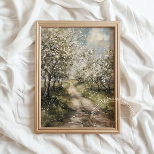 May include: A framed landscape painting in a gold-coloured frame. The artwork shows a path winding through a grove of trees with white blossoms. The painting has a soft, muted colour palette with green, brown, and white hues.