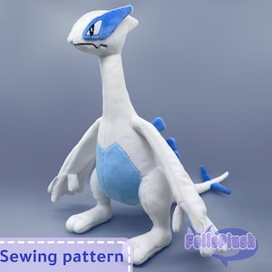 May include: White and blue plush toy of a mythical creature with a long neck and wings. The toy is standing on a grey surface. Sewing pattern.