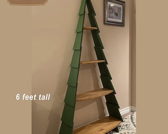 May include: A 6-foot tall green wooden Christmas tree bookshelf with five shelves. The shelves are made of natural wood and the tree is painted green. The tree has a gold star on top.