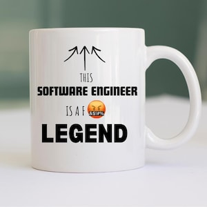 May include: White ceramic mug with a black handle. The mug features the text "THIS SOFTWARE ENGINEER IS A F LEGEND" in black, with an angry emoji and arrows.