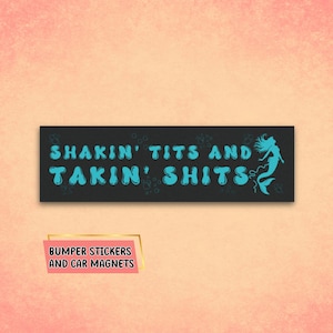 May include: Black bumper sticker with white text that reads "Shakin' Tits and Takin' Shits" in a bubble font. A blue mermaid silhouette is on the right side of the sticker.