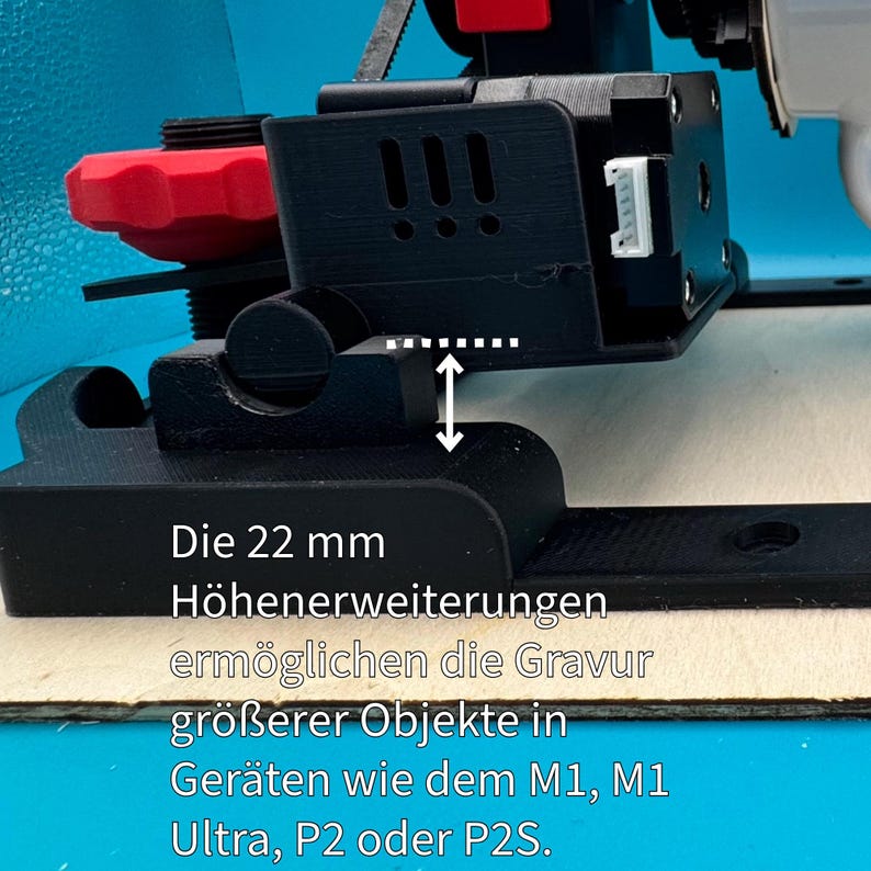 Pode incluir: Uma impressora 3D preta com uma ma&ccedil;aneta vermelha e uma extens&atilde;o de altura de 22 mm. O texto "Die 22 mm H&ouml;henerweiterungen erm&ouml;glichen die Gravur gr&ouml;&szlig;erer Objekte in Ger&auml;ten wie dem M1, M1 Ultra, P2 oder P2S." &eacute; vis&iacute;vel na base da impressora.
