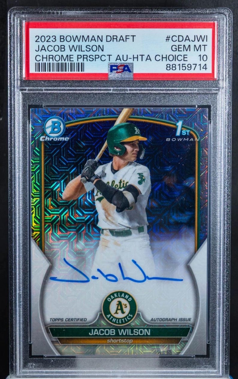 May include: A baseball trading card featuring Jacob Wilson in an Oakland Athletics uniform. The card is graded GEM MT 10 by PSA and includes an autograph. The card is from the 2023 Bowman Draft Chrome Prospect series.