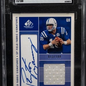 May include: A graded sports card featuring Peyton Manning in an Indianapolis Colts uniform. The card includes a fabric signature and is numbered 13/100. The card is graded a 9 by SGC. The text "CHASER!!" is at the bottom.