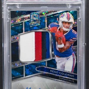 May include: A Keon Coleman 2024 Spectra football card with a patch autograph. The card features a blue, white, and red patch, and the text "CHASER!!" at the bottom. The card is graded GEM MT 10.
