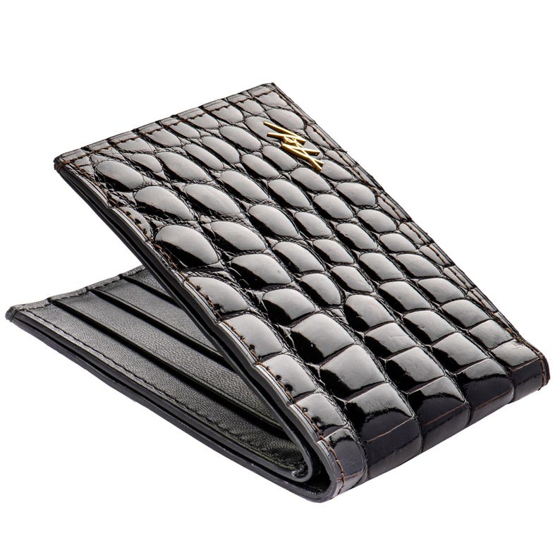May include: A black alligator leather wallet with a gold embossed logo. The wallet is folded in half and has multiple card slots.