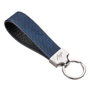 May include: A blue leather key chain with a silver key ring and a silver tag with the signature "Robert Graham" on it.
