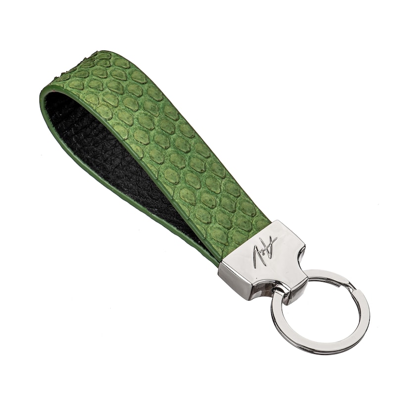 May include: Green leather keyring with a silver key ring and a silver tag with the signature "A.T." embossed on it.