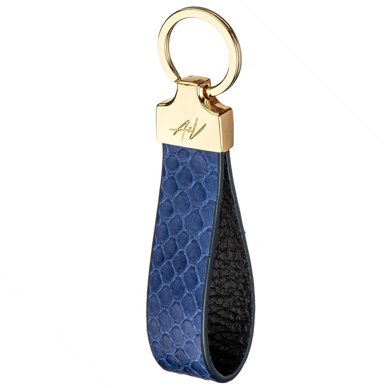 May include: A blue leather keychain with a gold ring and a gold metal tag with the initials "A&V" engraved on it.