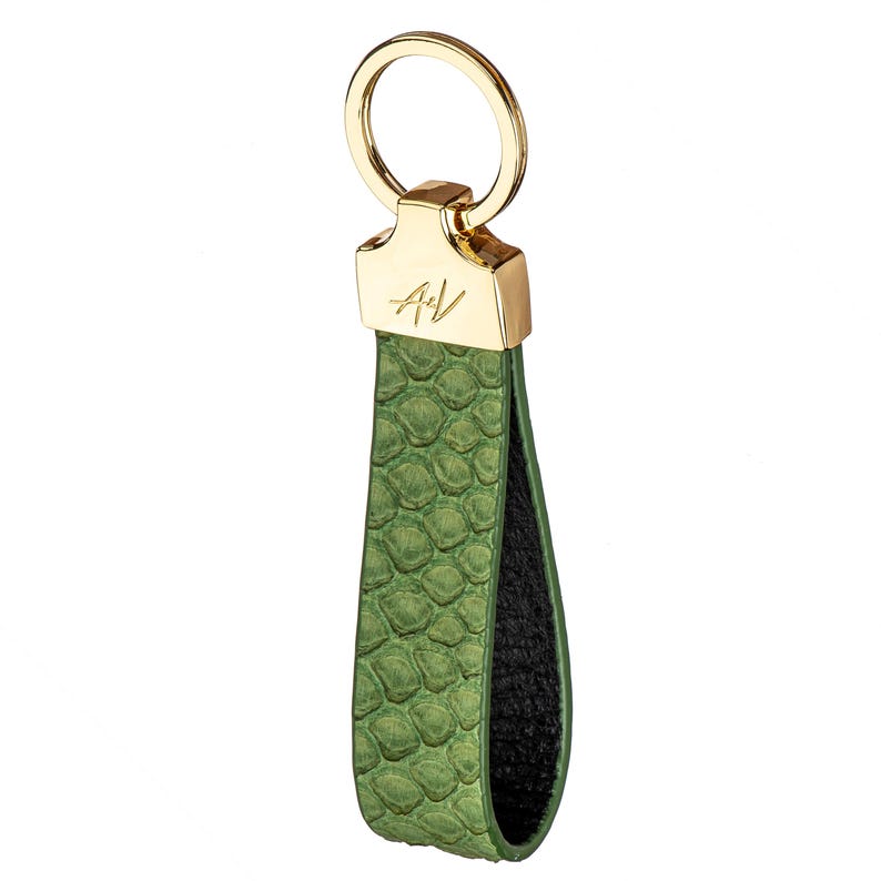 May include: A green leather keychain with a gold ring and a gold plate with the initials "A+V" engraved on it.