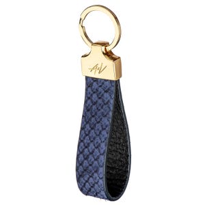 May include: A blue leather keyring with a gold ring and a gold metal tag with the initials "A+V".
