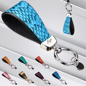 May include: A blue and black leather keyring with a silver ring and a silver charm with the word "Rift" on it. The keyring is made of genuine leather and has a snakeskin pattern.