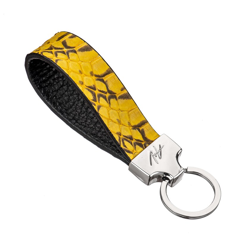 May include: Yellow and black snake skin leather key chain with a silver key ring and a silver tag with the text "Roy" on it.