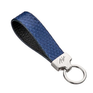 May include: A blue leather keychain with a silver key ring and a silver tag with the text "Art" on it.