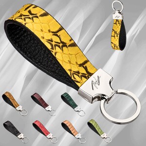 May include: A yellow and black leather keychain with a silver ring and a silver tag that says "AV." The keychain is made of genuine leather and has a snakeskin pattern.