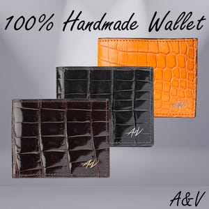 May include: Three leather wallets in different colors: brown, black, and orange. Each wallet has a crocodile-embossed pattern and the initials "A&V" embossed in gold. The text "100% Handmade Wallet" is at the top of the image. The text "A&V" is at the bottom of the image.