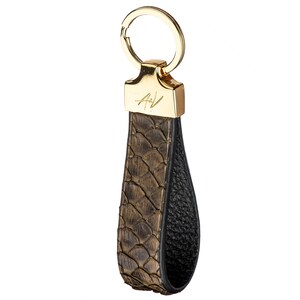 Może przedstawiać: Brązowy sk&oacute;rzany brelok do kluczy z złotym k&oacute;łkiem i złotą metalową zawieszką z wygrawerowanymi inicjałami "A/V".