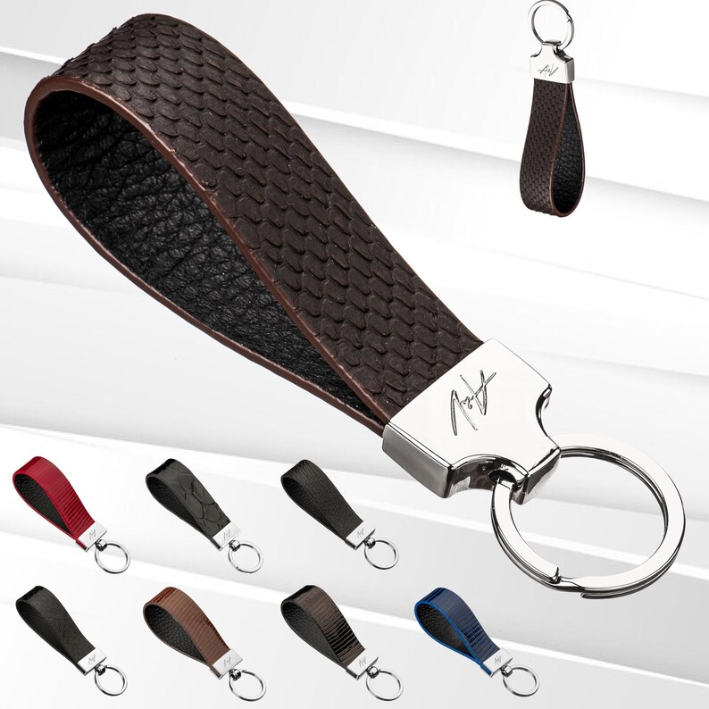 May include: A brown leather keyring with a silver key ring and a silver tag with the signature "Robert Graham".
