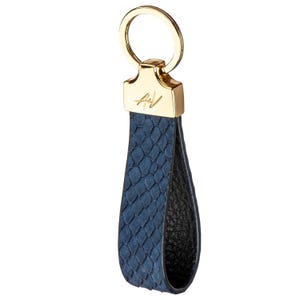 May include: A blue leather keychain with a gold ring and a gold metal tag with the initials "A+V".