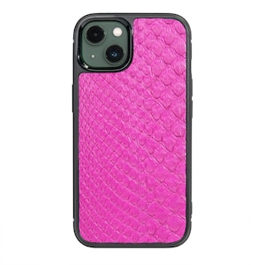 以下が含まれることがあります： 黒い縁取りとカメラの切り抜きのあるピンクのヘビ柄の携帯電話ケース