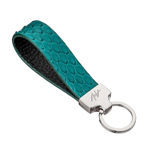 May include: A teal blue leather keychain with a silver key ring and a silver tag with the word "Rudy" engraved on it.
