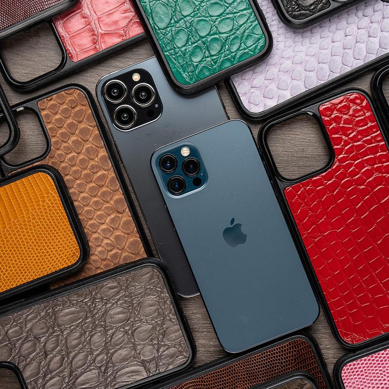 May include: A collection of phone cases with different patterns and colors, including red, green, brown, and black. The cases are made of leather and have a textured finish. The cases are designed to fit a variety of phone models.